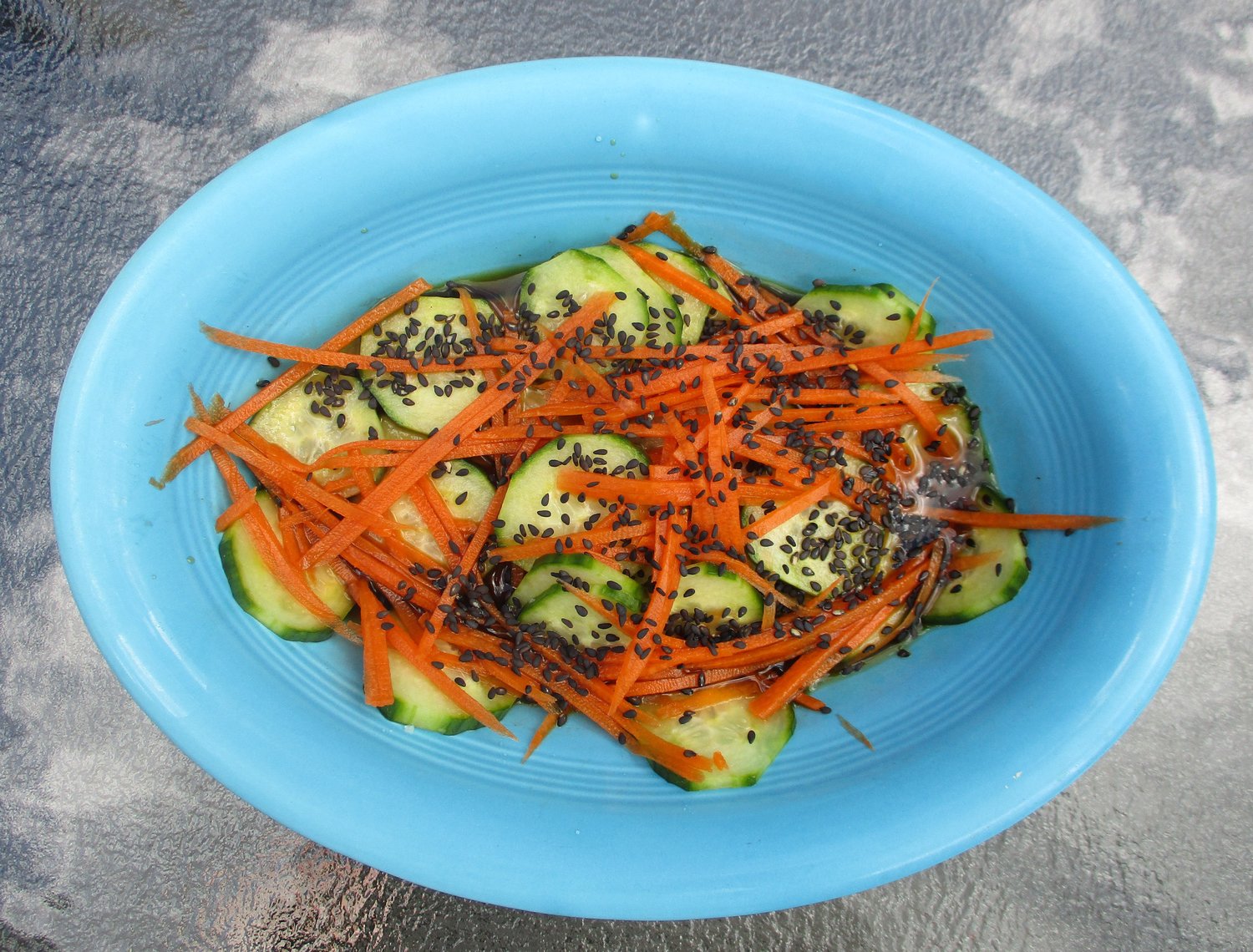 Japanese cucumber and grated carrot sunomono with black sesame seeds.